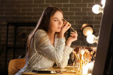 Geceleri soyunma odasında göz farı süren güzel bir kadın.