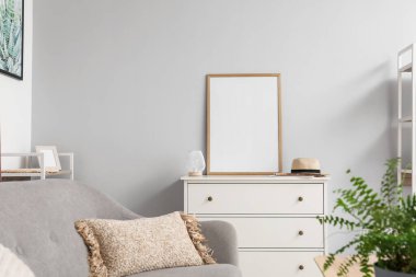 Açık oturma odasındaki çekmecelerin üzerindeki boş poster çerçevesi.