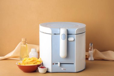 Arka planda kızarmış patates kasesi olan yeni bir kızartma makinesi.