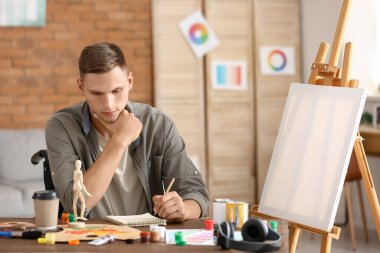 Genç engelli ressam atölyede resim çiziyor