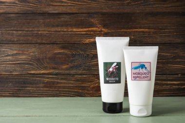 Koyu ahşap arka planda sivrisinek kovucu krem.