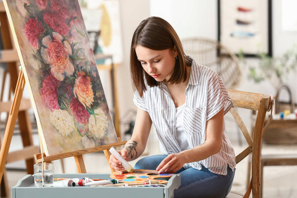 Young female artist painting in workshop