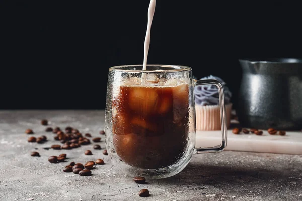 Versare Latte Una Tazza Vetro Con Gustoso Caffè Freddo Sul — Foto Stock