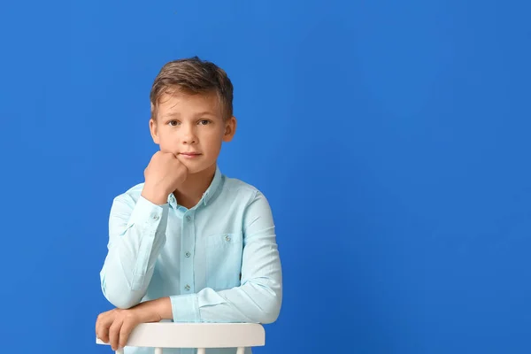 Liten Pojke Sitter Stol Mot Blå Bakgrund — Stockfoto