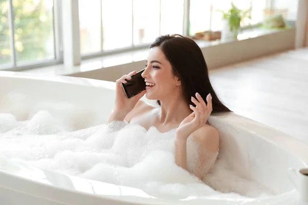 가집에서 목욕을 하면서 전화로 이야기하는 — 스톡 사진