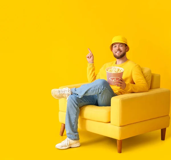 Young Guy Popcorn Sitting Armchair Pointing Something Color Background — Stock Photo, Image