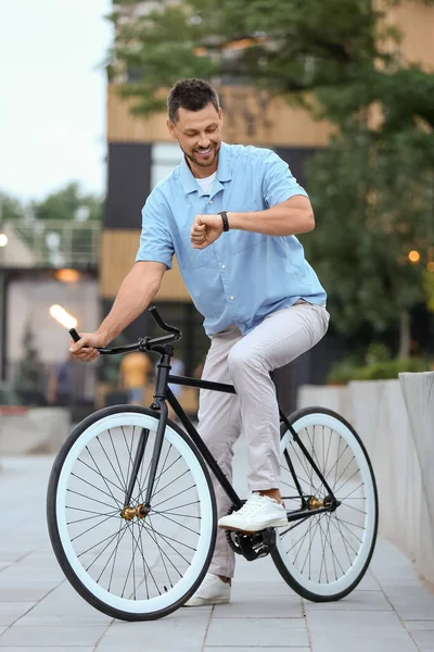 Mężczyzna Rowerem Patrząc Zegarek Ulicy Miasta — Zdjęcie stockowe