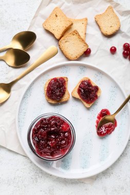 Bir kase lezzetli kızılcık reçeli ve beyaz arka planda sandviçler.
