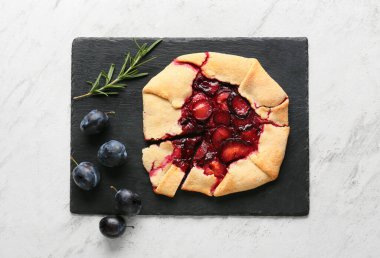 Açık arkaplanda taze erik galeti ve biberiye tahtası.