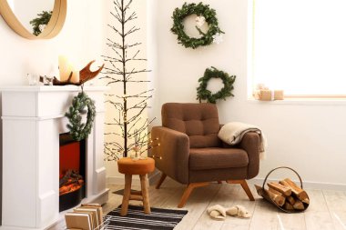 Elektrikli şömine ve rahat koltuk Noel için dekore edilmiş.