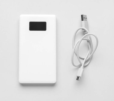 Işık arka planında modern güç bankası ve USB kablosu