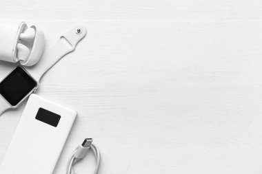 Modern güç bankası, kulaklıklar ve beyaz ahşap arka planda akıllı seğirmeler