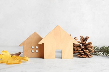 Beyaz arka planda köknar külahları ve düşmüş yaprakları olan ev figürleri. Kış konsepti