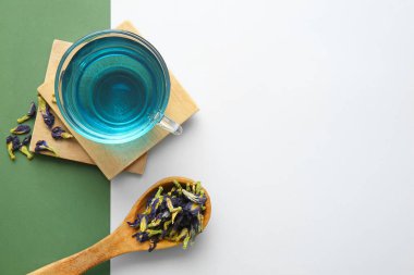 Bir bardak organik mavi çay ve arka planda kurutulmuş çiçekler.