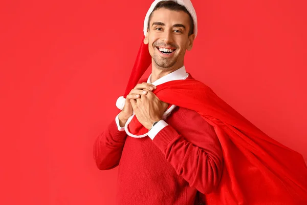 Kırmızı Arka Planda Noel Baba Çantalı Genç Adam — Stok fotoğraf