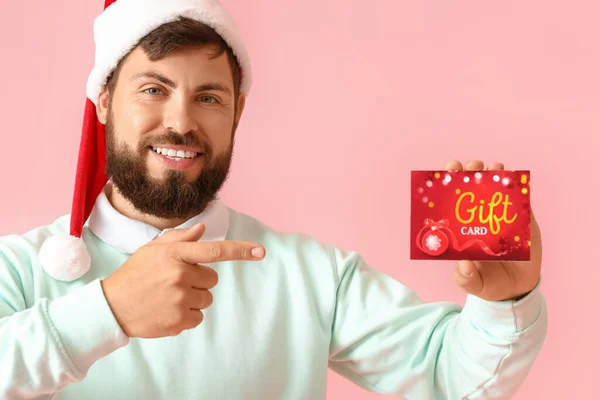 Bonito Homem Chapéu Santa Apontando Para Cartão Presente Fundo Rosa — Fotografia de Stock