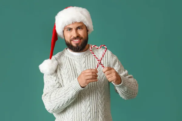 Schöner Mann Mit Weihnachtsmütze Und Zuckerstangen Auf Farbigem Hintergrund — Stockfoto