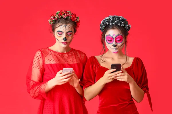 Stylish Women Painted Skull Faces Mobile Phones Color Background Celebration — Stock Photo, Image