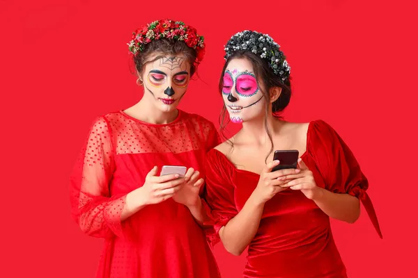 Stylish Women Painted Skull Faces Mobile Phones Color Background Celebration — Stock Photo, Image