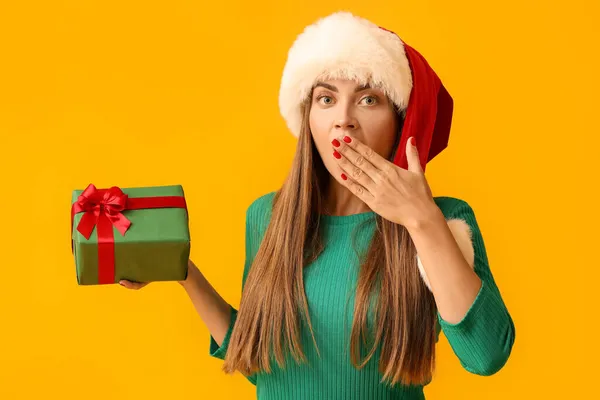 Shocked Young Woman Santa Hat Christmas Gift Yellow Background — Stock Photo, Image