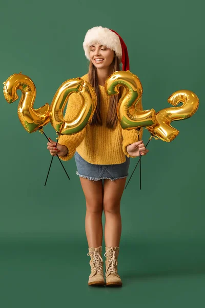 戴着圣诞帽 头戴绿色背景形状为2022型气球的年轻漂亮女子 — 图库照片