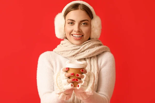 Mooie Jonge Vrouw Warme Oorkappen Met Afhaalkopje Koffie Rode Achtergrond — Stockfoto