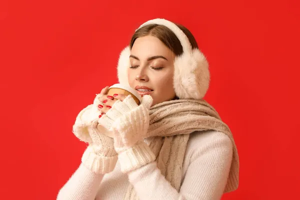 Mulher Bonita Earmuffs Quentes Bebendo Café Fundo Vermelho — Fotografia de Stock