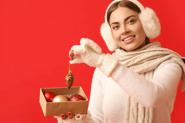 Kırmızı Arka Planda Noel Topları Olan Sıcak Kulaklıklı Güzel Bir — Stok fotoğraf