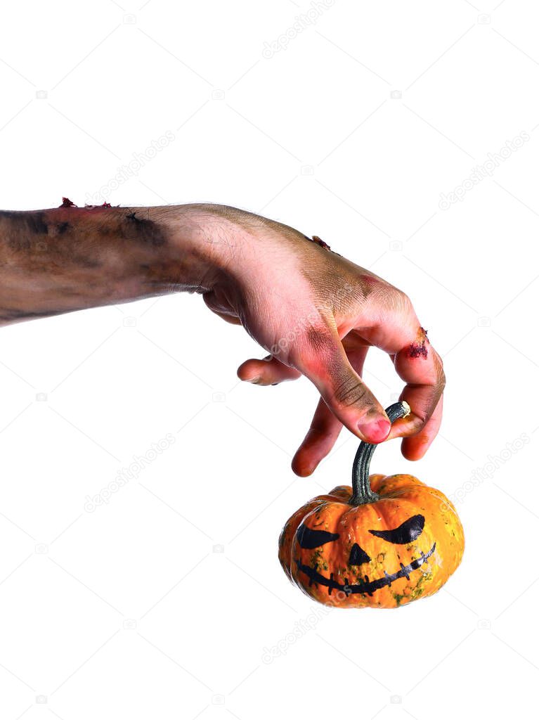 Hand of zombie with Halloween pumpkin on white background