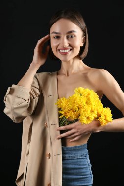 Siyah arka planda çiçek demeti olan seksi genç kadın.