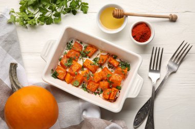 Lezzetli fırınlanmış balkabağı parçaları, bal ve baharatlar beyaz ahşap arka planda