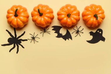 Bej arkaplanda Cadılar Bayramı dekoru olan balkabakları