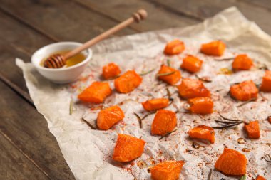 Ahşap zemin üzerinde lezzetli kavrulmuş balkabağı parçaları olan parşömen.