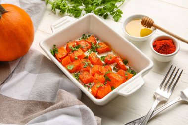 Lezzetli fırınlanmış balkabağı parçaları, bal ve baharatlar beyaz ahşap arka planda