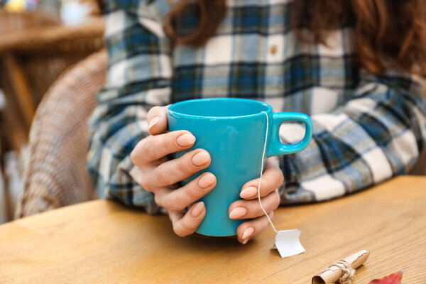 Женщина с голубой чашкой горячего чая за столом в кафе
