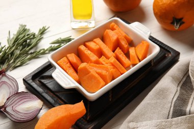 Beyaz ahşap zemin üzerinde balkabağı parçaları olan fırın tabağı