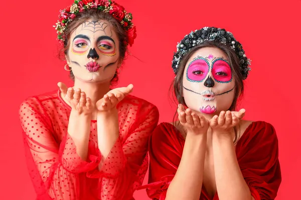 Stijlvolle Vrouwen Met Geschilderde Schedel Gezichten Blazen Kus Tegen Kleur — Stockfoto