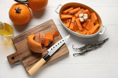 Beyaz ahşap arka planda taze balkabağı parçaları olan yemek tabağı ve yemek.