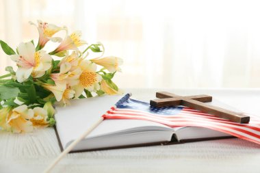 Kutsal İncil, haçlı, çiçekli ve masada Amerikan bayrağı