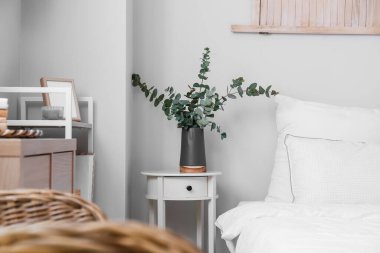 Açık yatak odasındaki komodinin üzerinde okaliptüs olan siyah vazo.