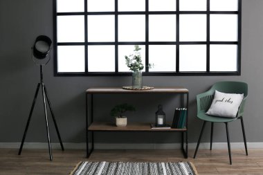 Camdan vazosu ve koltuğu olan karanlık modern bir oda.