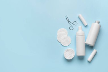 Losyon şişeleri, dudak kremleri, cımbızlar ve arka planda temiz pamuklar.