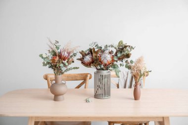 Yemek masasında kurutulmuş çiçekli vazolar.