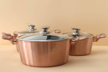 Hafif arka planda cam kepçeli yeni çelik tencereler