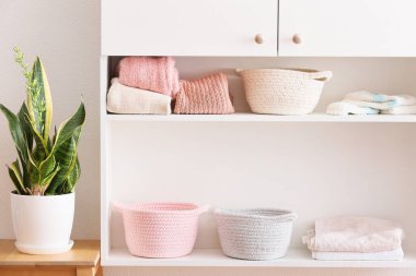 Sepetleri, temiz havluları ve kıyafetleri olan şık bir raf ünitesi.