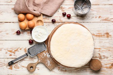 Hafif ahşap arka planda lezzetli khachapuri hazırlamak için taze hamur ve malzemelerle dolu bir pano.