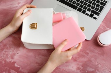 Tıbbi maske çantalı kadın eller, renkli arka planda çanta ve dizüstü bilgisayar