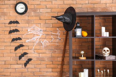 Tuğla duvarın yanında Cadılar Bayramı dekoru olan raf ünitesi