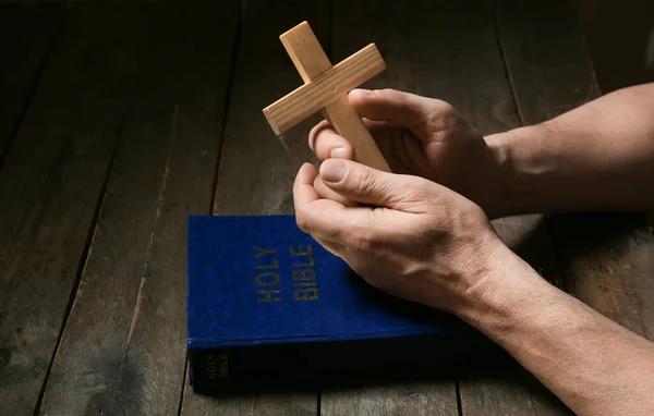 带着十字架和圣经的人 在黑暗的木桌旁 — 图库照片