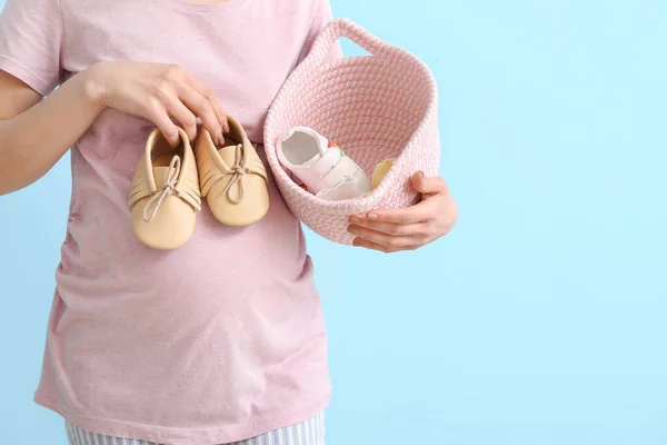 Young Pregnant Woman Holding Basket Baby Shoes Blue Background — Stock Photo, Image